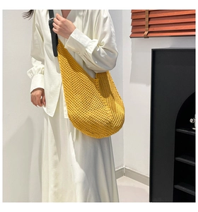 Detail of hand-crocheted yellow hobo bag with a black strap and woven mesh texture