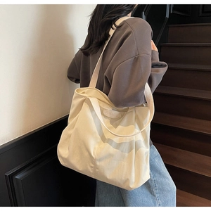 Large cream canvas tote bag with JUMAITU logo tag shown on person in a stylish setting