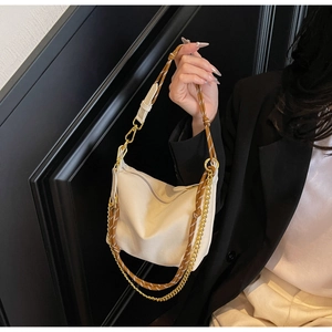 Detail of beige nylon crossbody bag featuring woven rope strap and gold metal chain