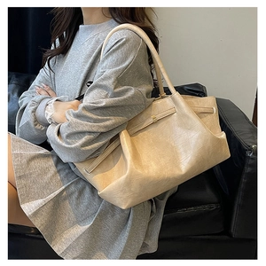Detail van de beige tas van imitatiekrokodillenleer met glanzende textuur en plooien