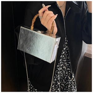 Detail of silver square box bag with metallic texture and natural bamboo handle