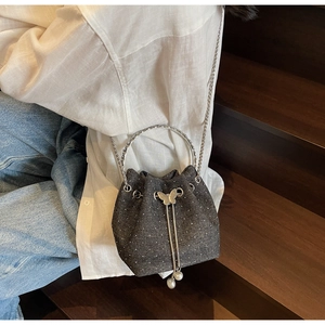 Detail of dark denim bucket bag with silver rhinestones and metal ring handle for women