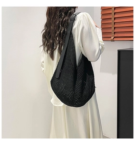 Detail of black woven mesh hobo bag featuring an adjustable leather shoulder strap