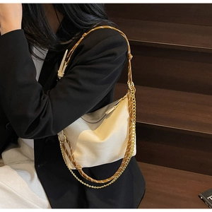 Detail of cream nylon dumpling bag featuring woven rope strap and gold chain accent