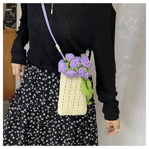 Detail of handmade knit bucket bag with 3D purple crochet roses and cream texture