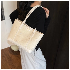 Detailed view of cream woven tote bag with 3D layered floral petals and metal brand logo