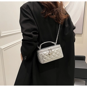 Close-up of silver quilted crossbody bag with heart charm and metal chain strap