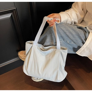Close-up of JOMAITU tote bag detail with logo patch and textured nylon fabric handle
