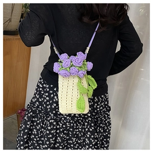 Detailed close-up of handmade cream knit bucket bag with purple 3D crochet flowers