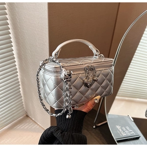 Close-up of a silver quilted chain bag with elegant heart pendant and metal texture