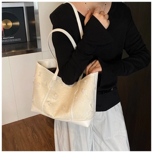 Detail view of large cream floral tote bag with lace patches and white faux leather handles