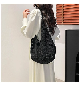 Detailed side view of a black crochet hobo bag styled on a person for a casual summer look