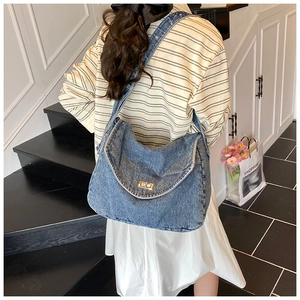 Vista posteriore della modella con una grande borsa tote in denim lavato con fibbia d'oro