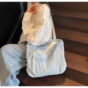 Close-up of a light blue canvas tote bag worn over the shoulder by a model
