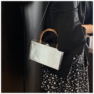 Detail of silver leather handbag with natural bamboo handle and metal chain strap