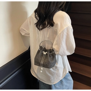 Detail of grey bucket bag featuring white rhinestone dots and butterfly metal buckle