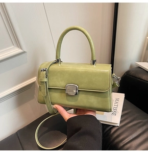 Close-up of light green PU leather bag with silver metal buckle and top handle