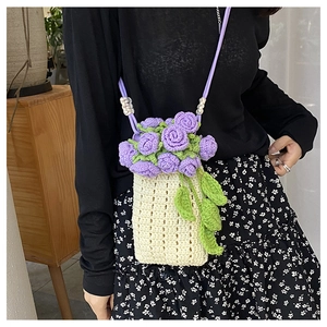 Close-up of handmade cream knit bag featuring purple crochet roses and green leaf details