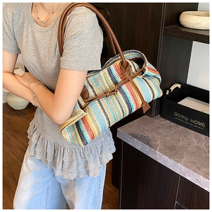Detail of colorful woven straw tote bag with brown leather handles on shoulder