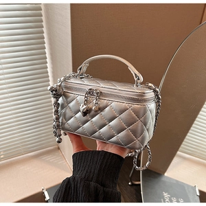 Detail of silver quilted handbag with metal chain and heart-shaped zipper pendant