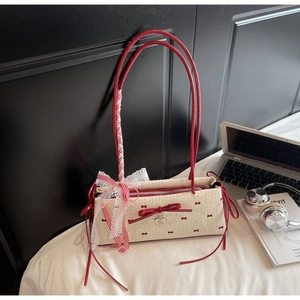 Dettaglio della borsa bianca a pois con grande fiocco in pelle rossa e cuore