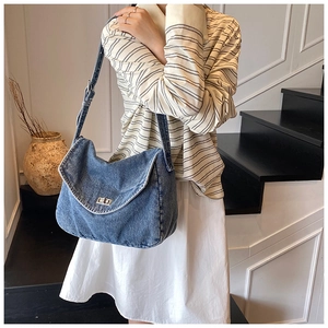 Dettaglio della borsa a tracolla in denim blu con patta vintage e chiusura a girello