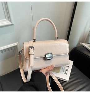 Detailed close-up of cream pink leather handbag with silver clasp and adjustable strap