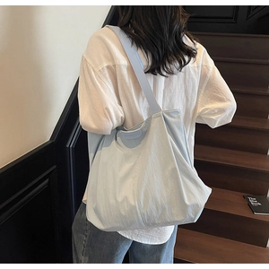 Detail view of large light blue canvas tote bag on stairs featuring clean stitching and logo