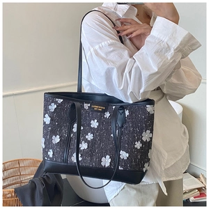 Detail of tweed tote bag featuring 3D floral patches and leather trim for women