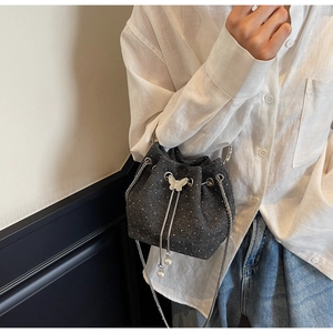 Close-up of denim bucket bag with pearl drawstring and silver butterfly buckle detail