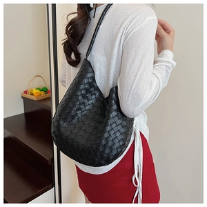 Gros plan d'un sac hobo tissé noir avec une bandoulière assortie sur un mannequin