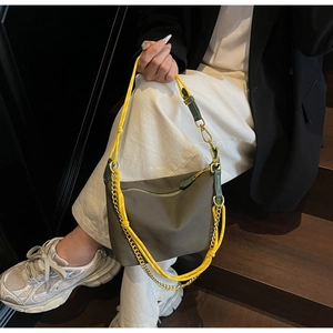 Detail of olive green nylon dumpling bag featuring yellow woven strap and gold chain