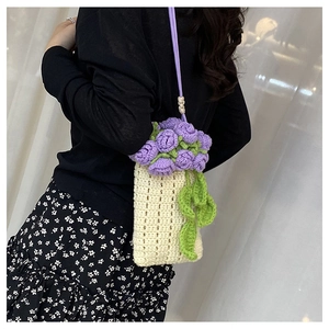 Detail of hand-crocheted cream bucket bag with purple rose and green leaf accents