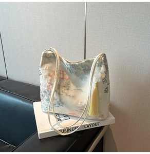 Close-up of Chinese style embroidery on a cream bucket bag with elegant tassel detail