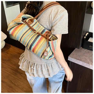 Close-up of colorful striped woven straw tote with brown leather shoulder straps