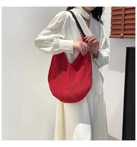 Detail of red hollow crochet hobo bag with knit texture and black shoulder straps