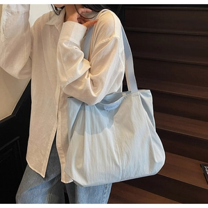 Detail of light blue canvas tote bag showing textured fabric and embossed leather brand tag