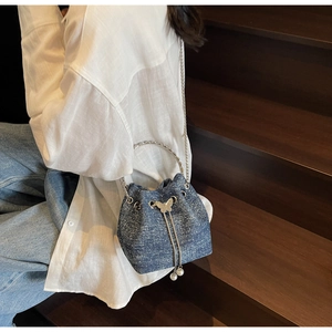 Detail of blue denim bucket bag with silver butterfly buckle and pearl pendant accents