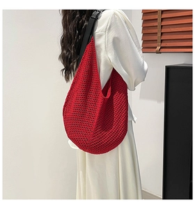 Detail of red crochet tote bag with wide black shoulder strap shown on model's back