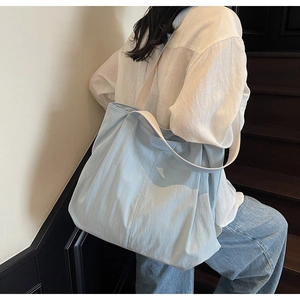 Detail of the light blue canvas tote bag with contrast cream strap and leather brand label