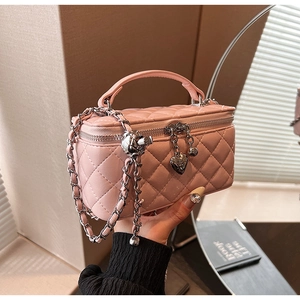 Close-up of pink quilted mini bag featuring heart zipper pull and silver chain strap