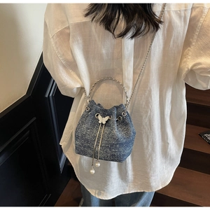 Detail view of denim texture cloud bag with silver ring handle and pearl charms