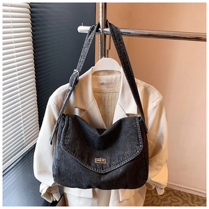Dettaglio borsa in denim grigio con patta, chiusura a rotazione in metallo argento e tracolla