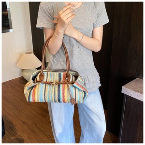 Close-up of colorful striped woven straw bag with brown leather handles and metal buckle