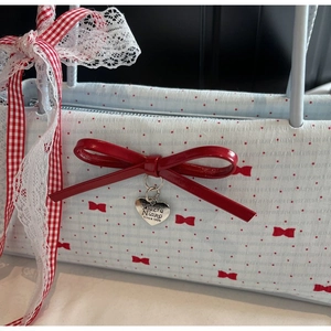 Dettaglio della borsa azzurra a pois con fiocco rosso e ciondolo a cuore
