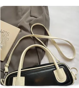 Detail of contrast stitching and detachable strap on black and white leather baguette bag