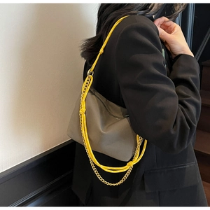 Detail view of khaki nylon bag with yellow shoulder strap and gold chain accent