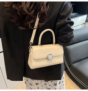 Modern white leather crossbody bag shown on a model in a sleek blazer background