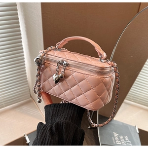 Detail of pink quilted leather bag with heart charm and gold metal chain strap