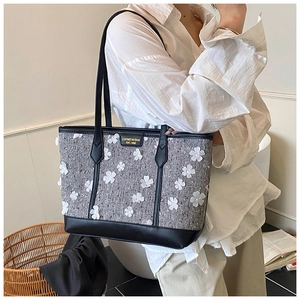 Detail of grey tweed tote bag featuring white 3D flower patches and black leather trim